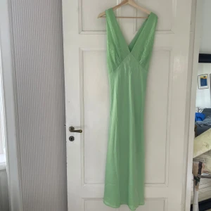 Grön midi klänning strl 42 - Superfin grön midi klänning i grön. Djup v-rigning. Små emroideri på brösten. Inga ärmar. Aldrig använd, prislapp kvar. 