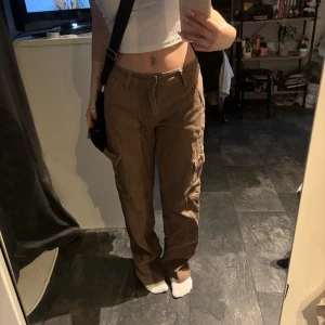 Bruna cargo byxor - Ett par lowwaist cargo byxor i jeans material. Jag är 160cm och har trampat sönder lite bak på (finns bild med) 