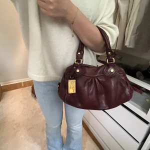 Vinröd marcjacobs väska  - Snyggaste väskan. Lånade bilder. Inte bästa skick utan tydligt en vintage väska så därav priset. Då den har defekter här och där och smutsig där inne! Men inga hål,Äkta självklart sparar inte på kvitto eller dustbags men den är iaf köpt i butik . 