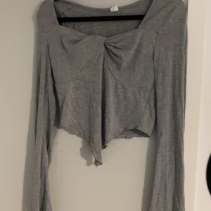 Grå tröja  - Grå topp, urringad skön och ganska tunn, inte använd så mycket bara legat i garderoben utan att ha kommit till användning därför valde jag att sälja denna 