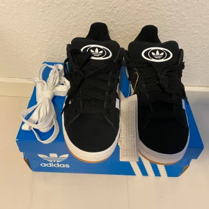 Nya Adidas Campus 00s -storlek 36 2/3 - Adidas Originals Campus 00 s j Storlek: 36 2/3 Färg: Svarta (Core Black) Ingår även vita skosnören.  Nya o oanvända. Kommer ej från någon massbeställning från utomlands. Köpta här i Sverige och därmed garanterat äkta.  