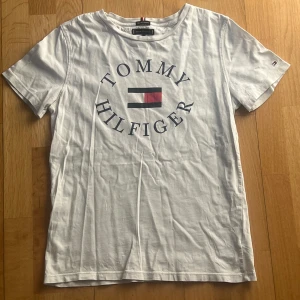 TOMMY HILFIGER T-SHIRT - Säljer denna feta Tommy Hilfiger tröjan nu i storlek 164 barnstorlek, sitter som xs eller något mindre. Använd i ca 6 månader tills den blev för liten, skick 8/10, inga ordebtliga defekter. Hör av er om ni har några funderingar!