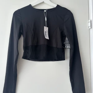 Crop top - Svart crop top med mesh längst ner. Ny med etikett kvar.