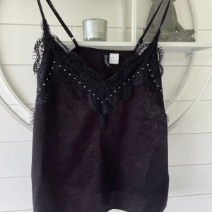 Svart linne - Svart linne med spets och stenar. Storlek 32 från hm. Tyget är lite nopprigt.