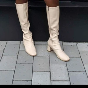 Beiga/benvita boots - Skitsnygga trendiga knähöga boots, oklart material men låg klack så bekväma att gå i. Dragkedjan har strulat nån gång, därav lågt pris men inget problem nu när jag testar. Har strl 38-39 o de passar!  