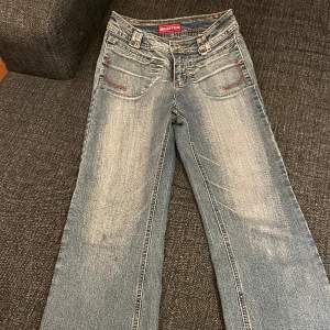 Super snygga Musketeer jeans i starkt material. Finns några defekter som två små fläckar och en större fläck. Fläckarna syns mindre i verkligheten. Dragkedjan vid gylfen är trasig men går att stänga med knapp. Passar 160/163cm (se midjemått)
