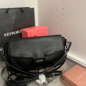 Snygg svart väska - Svart väska från BikBok med tillhörande långt band men som även bara kan bäras på axeln, helt oanvänd 🤍Pris kan självklart diskuteras!