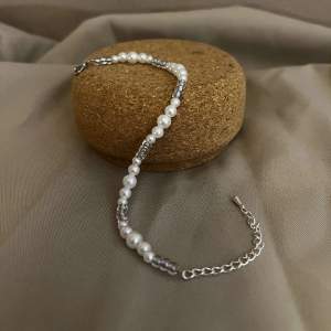 Armbandet Izabelle består av olika storlekar av vita pärlor med silvriga små pärlor. Låset och kedjan är i silver.  Namn: Izabelle Längd: Hela 23 cm Pärlor 15,5 cm Pris: 99 kr
