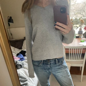 Ljusgrå stickad tröja - Använd men i fint skick! Säljer då den aldrig kommer till användning. Mycket snyggt basic plagg och skön på! Fin passform med v-ringning.