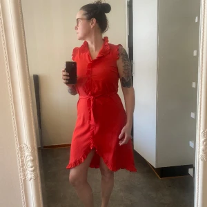 Klänning  - En sommarklänning med knyt. Knappar ner till midjan. Nederdelen består av dubbla tyg. Mindre risk för genomskinlighet. 