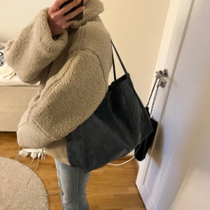 Handväska - Handväska i dov blågrå färg av fakeskinn. Tidigare köpt på plick därav vet jag ej vart den kommer ifrån. Fler bilder vid önskemål