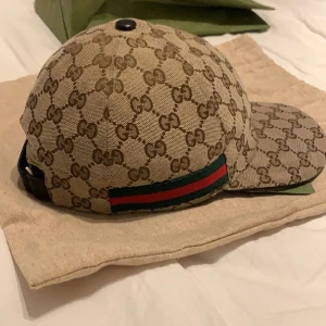 Gucci keps  - En äkta Gucci keps, nästan helt ny använd ett par gånger, skicket är 9/10. Allt ingår i kepsen och för fler frågor skriv Dm. Finns bevis på att den är äkta.
