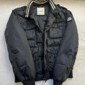 Moncler field jacket - Skit snygg Moncler field jacket i modell: Cahors!  Äkta såklart, kolla bild 3. Modellen säljs inte längre. Fint skick bara att ena zippen på dragaren är sönder, annars felfri.