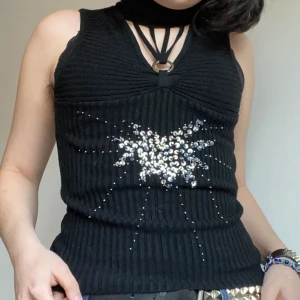 Kamila N.D.K-topp  - Unik vintagetopp från det polska märket Kamila N.D.K. Cutout och harnessdetalj samt paljetter på framsidan. Polokrage.  Skönt, tjockt tyg. Hör gärna av er vid frågor! :)