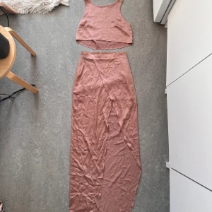 Matchade set med kjol och topp - Co-ord set i satin från Rebecca Stella. Croppad topp och kjol med slits framtill. Kjolen är hög i midjan 