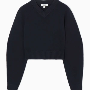 Cos ”cropped v-neck wool jumper” i marinblått, strl L - Cos stickad tröja ”cropped v-neck wool jumper”, i jättefint skick, nästan helt oanvänd, marinblå, i storlek L. Originalpris 900kr.