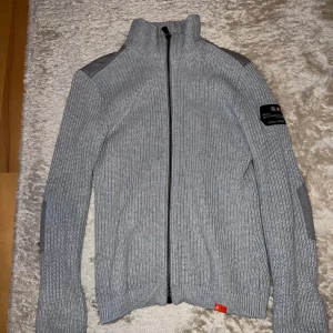 Sail Racing Stickadtröja Grå - Säljer grå stickad Sailracing tröja. Unik tröja som inte längre säljs i butiker. Storleken på tröjan är S. Tröjan är tajt vid armarna men lång i längden, passar den som har S eller M. Skriv vid fler frågor eller bilder!