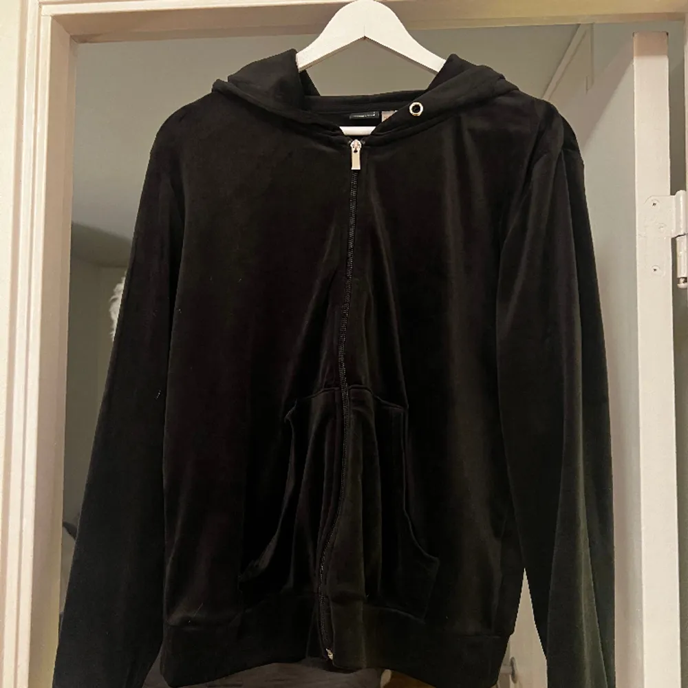 En svart hoodie i velour med dragkedja. Hoodien är normal i storleken och är sparsamt använd och det finns inga skador eller liknande på den🥰  Den är i storlek L och är ifrån Ginatricot i deras modell Cecilia 95% polyester 5% elastan. Hoodies.