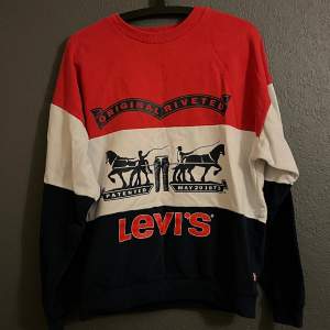Sweatshirt från Levi’s. Röd, vit och marinblå med tryck på framsidan. Väl använda så den är lite nopprig men inga större skador! Storlek 16 år, skulle säga s/m.  Köpare står för frakt!