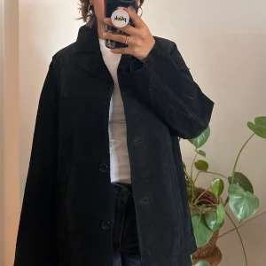 Skinnjacka i mocka  - Svart skinnjacka i ett mocka material. Tyget på jackan är hårt vilket gör att formen på jackan håller bra.  Står att den är strl 46, men funkar bra på mig som är 36-38. Köpt jackan second hand, men tycker skicket är bra. 