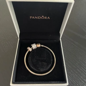 Väldigt fint Pandora armband  - Väldigt fint armband med tillhörande berlocker. Går att köpa till och byta ut berlockerna. Guldpläterst lås. Berlocker köpta för: 1300kr