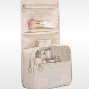 Beige necessär för resor - En praktisk beige necessär med flera fack och dragkedjor, perfekt för att organisera toalettartiklar och smink under resor. Necessären har en krok för upphängning och ett handtag för enkel transport.i mycket bra skick, behöver rengöras från fläckar vg och se sista bilden.