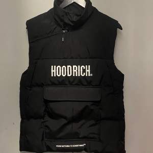 **Hoodrich Väst - Svart - M - Helt Oanvänd och Som Ny**  Säljer en svart Hoodrich väst i storlek M. Helt oanvänd och som ny. Perfekt för dig som vill ha en stilren och trendig väst i din garderob. Missa inte chansen!