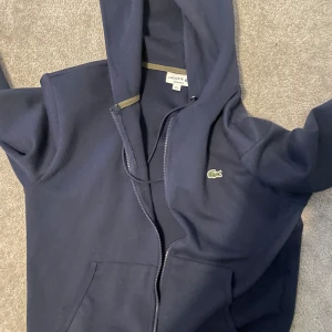 Lacoste zip - Extremt snygg lacoste zip hoodie, säljer för den inte används särskilt mycket. Äkta såklart, inga defekter eller liknande. 