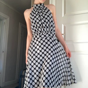 Klänning - Så fin svart silkes klänning med vita prickar från märket Sara Kelly. Öppen rygg och snören man knyter till en rosett!🩶 stretchit material! Klänningen är endast använd en gång och är så gott som ny🩶