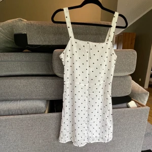 Vitprickig sommarklänning  - Vit klänning med svarta prickar från H&M. Helt oanvänd. Storlek 40, liten i storleken. 