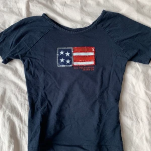 T-shirt med amerikansk flagga  - Har ingen lapp med storlek eller märke, men jag gissar att den är S. Passar som en babytee 🩷