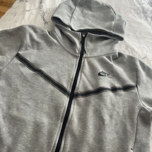 Nike tech grå  - S / äkta Nike tech köpt på JD för 1400 säljer för 600 jätte bra skick förutom en liten fläck (se bild)  Priset  går att diskutera 