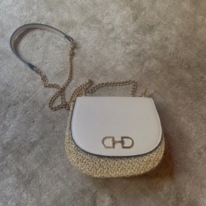 Axelremsväska  - Märke: H&M Färg: Beige, kaki och guld Storlek: 20cm x 17cm x 7cm Söt axelremsväska som passar perfekt till stranden eller en mysig middag!