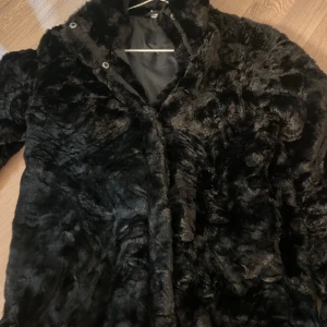 Fluffig svart jacka för barn. - Har bara använt den 1 gång. Jätte skön att ha på. 