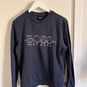 Marinblå sweatshirt från Hugo Boss i storlek M. Använd men i bra skick därför bra pris. 