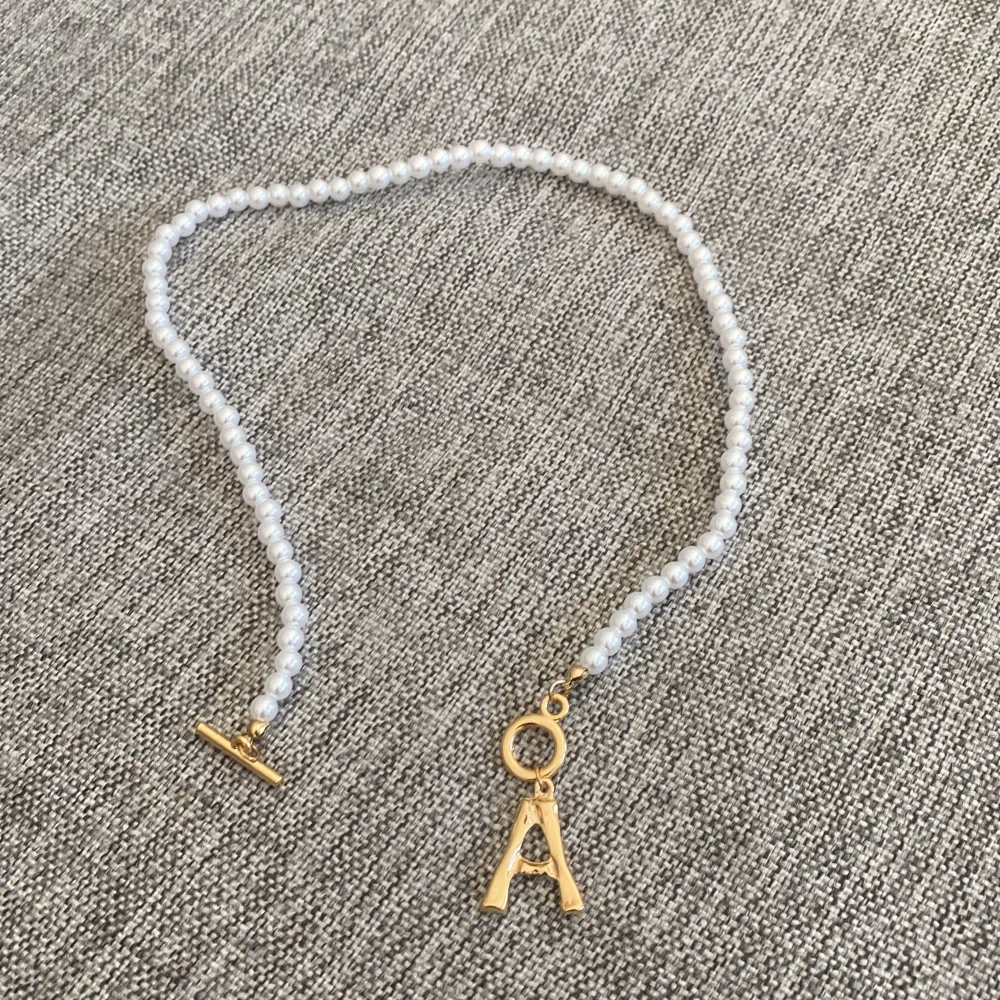Ett fint halsband med pärlor och initialen A. Accessoarer.