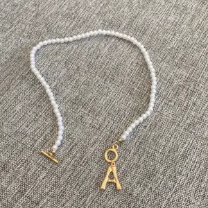 Ett fint halsband med pärlor och initialen A
