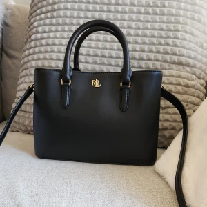 Ralph Lauren väska - Ralph Lauren väska med lappen kvar, givetvis äkta med alla stämplar. Helt oanvänd och i nyskick✨️Perfekt smidig storlek(inte för stor eller för liten). Nvärde: 4899:- Dustbag medföljer. Det längre väskbandet är avtagbart👍Hämtas i stan