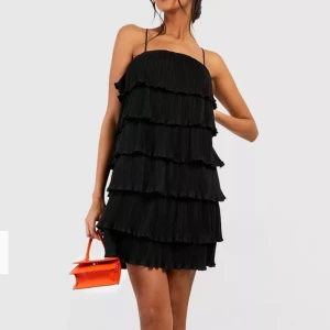 Svart kort volangklänning - Superfin plisserad kort klänning med knytning i ryggen, aldrig använd och true to size🥰