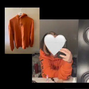 Oragne hoodie med tryck ifram och på armarna. Spegelbilden visar färgen mer korrekt. Köpte den på Plick och den är ganska använd.