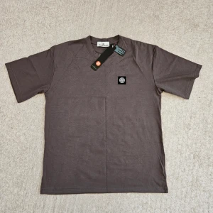 St*ne Isl*nd T-shirt M/L - Den här T-shirten är en perfekt kombination av stil och komfort! Trots att den är märkt som storlek M, är den faktiskt oversized och känns mer som en L, vilket ger dig en avslappnad och trendig look. Tillverkad av högkvalitativa tyg.