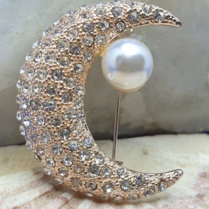 Brosch  - .Måne / Halvmåne med kristaller  - Den här broschen föreställer en måne och måtten är ca 4 ×3.5 cm. Roseguldfärgad metall med vacker ytstruktur och kristaller samt en pärla.  Grymt snygg brosch, oanvänd, nyskick