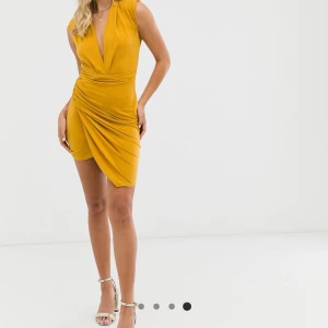 Senapsgul, rynkad miniklänning med djup urringning - Klänning är i bra skick och använts 2 gånger bara. Av polyester