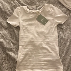 Vit T-shirt  - Vit T-shirt ifrån hm i storlek xs som är helt ny och inte använd en enda gång. Prislappen kvar!