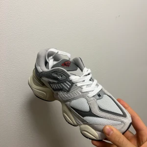 New Balance 9060 - New Balance 9060 grå Storlek:38   New Balance 9060 RAIN CLOUD  - Ovandel av mesh med topplager av mocka  - Transparent CV-detalj på hälen   - ABZORB - och SBS-stötdämpning   - Yttersula i gummi  