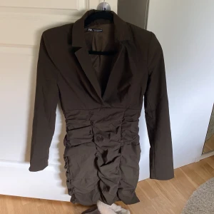 Klänning - Militärgrön klänning. Kavajmodell upptill med v-ringning och figursydd nedtill med två fejk fickor. Supersnygg passform! Köpt för ca 700kr. Tjockare, finare och bekvämt material!! Använd en gång