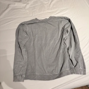 Grå tjocktröja - Bra skick små slitage på muddarna grå tjocktröja med vitfläckig design