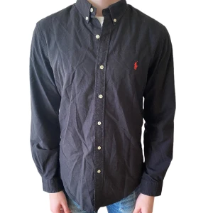 Ralph Lauren skjorta - En svart Ralph Lauren skjorta i storlek m, bra skick/ inga defekter. Modellen är 185 cm lång. Tveka inte att höra av dig om det finns några frågetecken. Nypris 1500kr