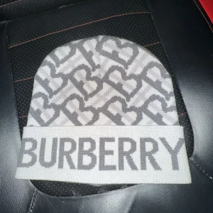 Burberry Mössa - Burberry mössa helt ny och oanvänd. Är perfekt för denna tid av året med väldigt vacker passform. Den har inga defekter och den har ritkigt fin färg. Ganska sällsynt. Färgen på texten är lite mörk grå men ljuset på bilden får den se ljus ut.