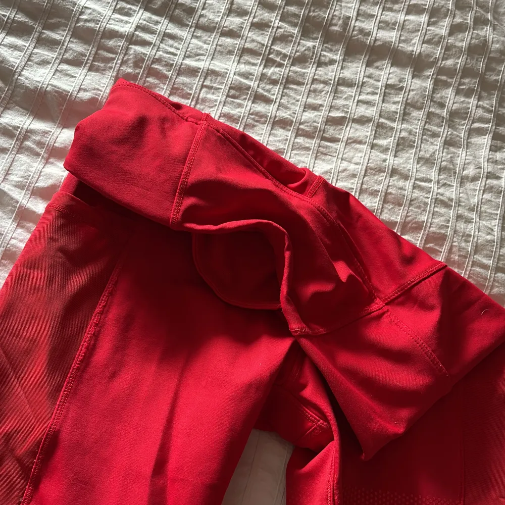 Snygga röda tights med tre fickor. Två större på sidan av låren och en mindre bak i midjan. Finns tillhörande tröja att köpa till. . Sport & träning.